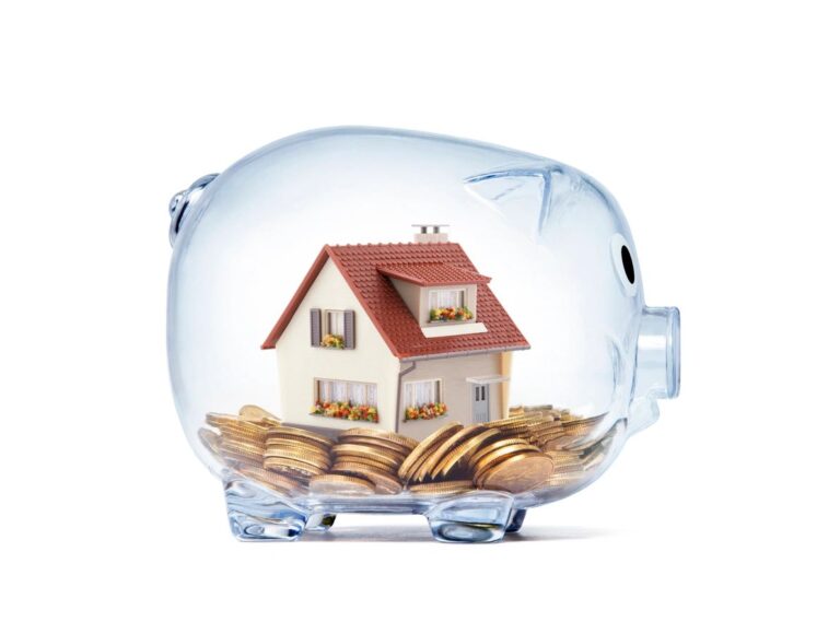 a glass piggy bank with coins and small model house in it