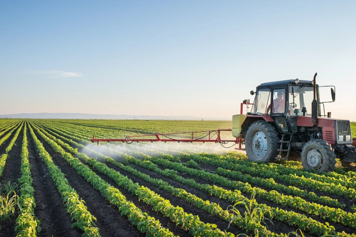 a tractor spraying water on some crops in a large field