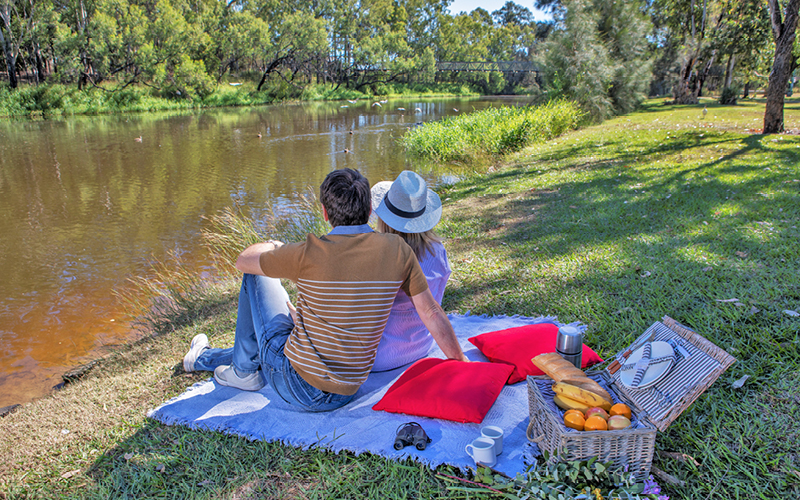 a couple having a picnic by the creek